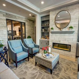 A modern living room with a cozy fireplace, stylish armchairs, and elegant decor.