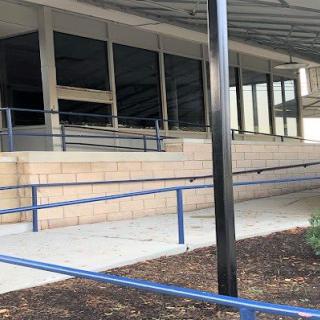 A building entrance featuring a series of ramps with blue handrails.