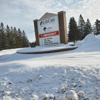A snowy scene featuring a prominent outdoor sign surrounded by a winter landscape.