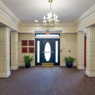 A well-decorated lobby with a chandelier and plants on either side of the entrance.