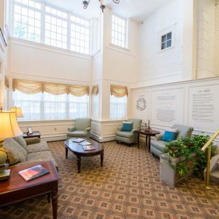 A spacious living room with high ceilings, large windows, and cozy furnishings.