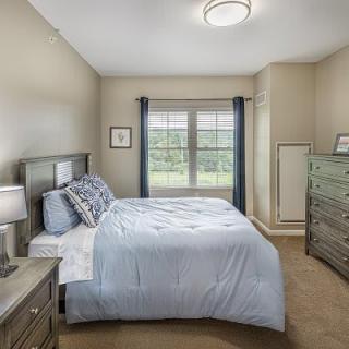 Cozy bedroom with a neatly made bed and large window.