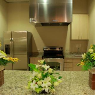 A modern kitchen featuring a granite countertop adorned with floral arrangements and stainless steel appliances.