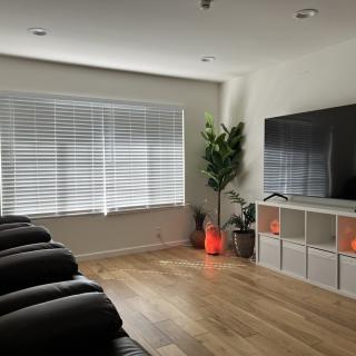 A modern, minimalist living room with a large TV, comfortable seating, and stylish decor.