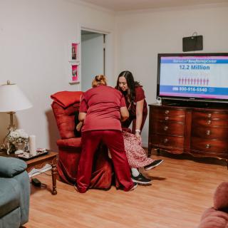 Caregivers assist a person in a home setting.