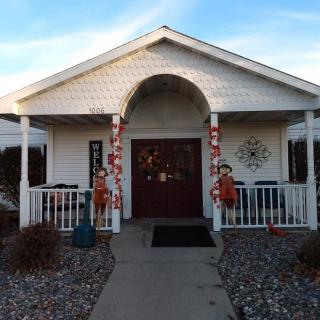 A white house with a decorated entrance and porch, featuring holiday ornaments.