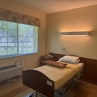 A well-lit hospital room featuring a single bed and a window allowing natural light.