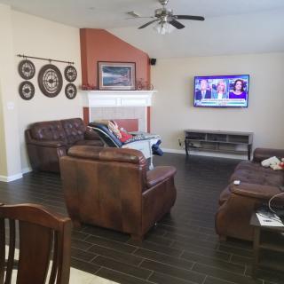 A cozy living room with leather sofas, a television mounted on the wall, and a fireplace.