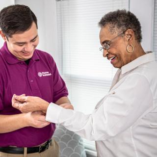 A healthcare professional assists an elderly patient with a warm smile.