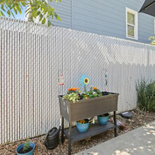 A well-maintained garden area featuring a planter box with colorful flowers, set against a wooden fence.