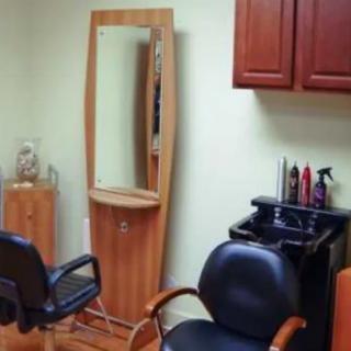 A cozy salon setup with chairs, a large mirror, and hair styling products.