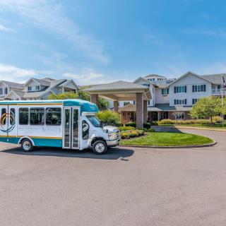 A shuttle bus parked in front of a residential building on a sunny day.