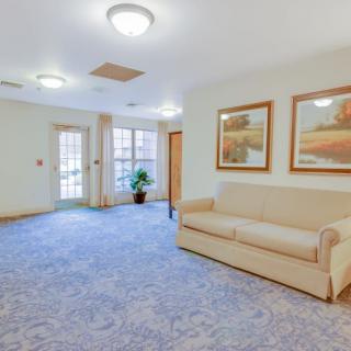 A spacious lobby area with a comfortable sofa, artwork on the walls, and soft carpet flooring.
