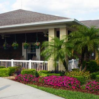 A charming building surrounded by lush landscaping with palm trees and vibrant flowers.