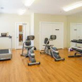 A small gym with various exercise equipment including a treadmill, elliptical, and stationary bike.
