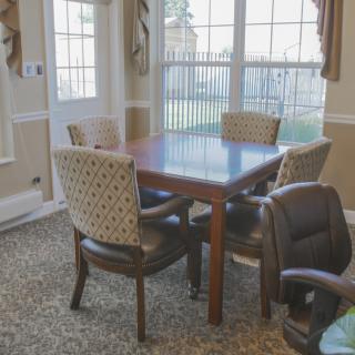 A cozy dining area with a wooden table and upholstered chairs near large windows.