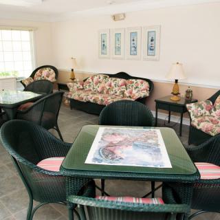 A cozy living room featuring floral sofas and wicker chairs around a small table.