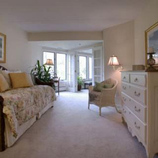 A cozy bedroom featuring bright natural light, elegant decor, and comfortable furnishings.