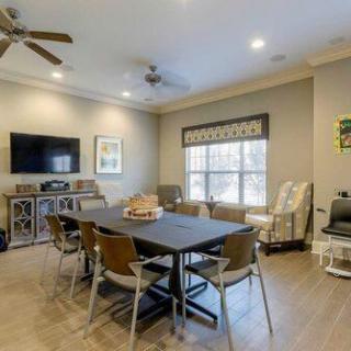 A modern living room with a dining table, chairs, and a wall-mounted television.