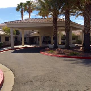 A building entrance with a driveway and palm trees in the foreground.