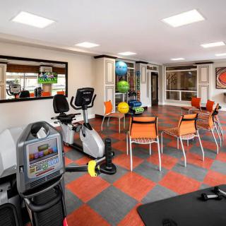 A brightly lit gym with exercise equipment and seating area.