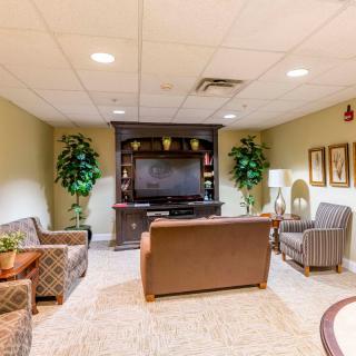 A cozy living room with comfortable seating, a TV, plants, and artwork.