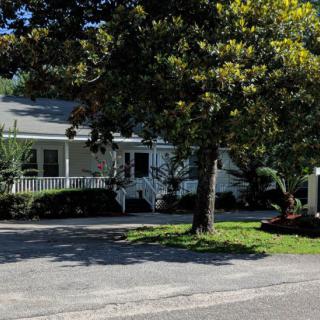 A suburban house with a porch and surrounding trees on a sunny day.