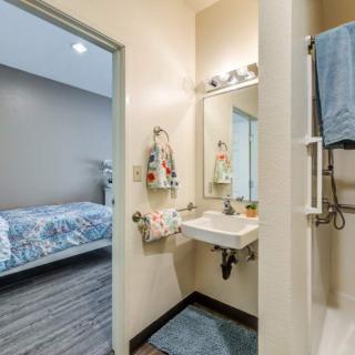 A cozy bathroom with a view into an adjoining bedroom, featuring a sink and mirror setup.