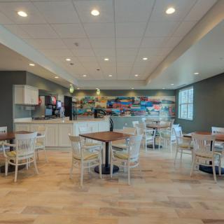A modern cafe with multiple tables and chairs, featuring colorful wall art.