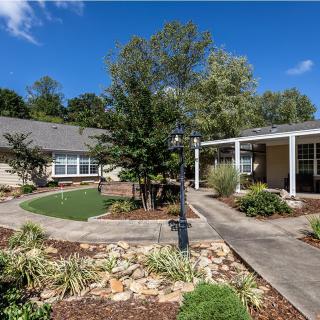 A picturesque garden with a charming house, surrounded by lush greenery and blue skies.