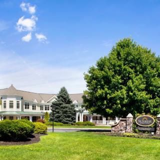 A scenic view of a large building surrounded by lush greenery and a bright blue sky.