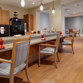 A modern dining area with wooden flooring, comfortable chairs, and pendant lighting.
