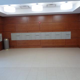 A modern lobby with wood paneling and a row of mailboxes.