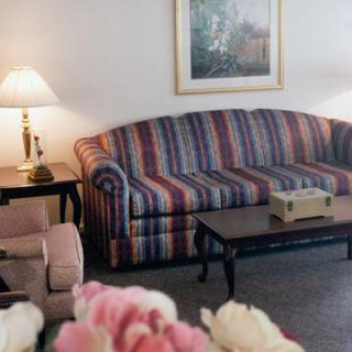 A cozy living room featuring a striped sofa, a side table with a lamp, and a framed painting on the wall.