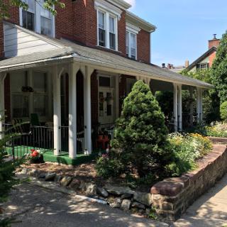 A charming residential house featuring a welcoming porch and beautiful landscaping.