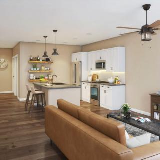 A modern open-concept kitchen and living room with sleek furnishings and warm wood flooring.
