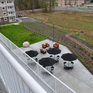A view of an outdoor patio area with tables, chairs, and umbrellas near a building.