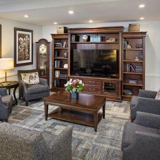 A cozy living room with a large entertainment center, comfortable seating, and elegant decor.