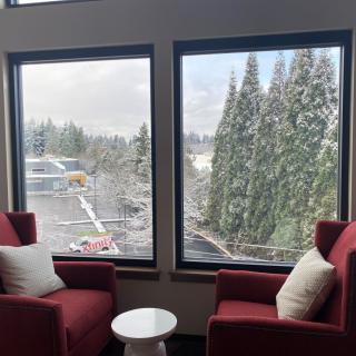 A cozy seating area with red chairs overlooks a snowy landscape through large windows.
