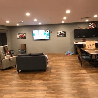 A modern living room with a sofa, television, and wooden flooring.