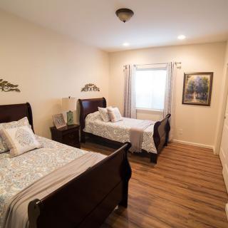 A cozy bedroom featuring two single beds with wooden frames, complemented by a warm wood floor, and enhanced with decorative wall art.
