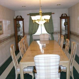 A formal dining room with a long table, matching chairs, and a chandelier.