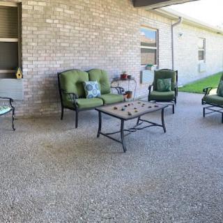 A cozy patio area with green cushioned furniture and a coffee table set against a brick wall.