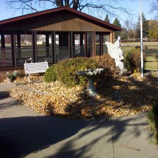 A peaceful garden scene with a bench and statue near a gazebo in autumn.