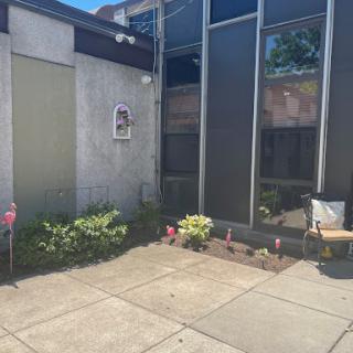 A view of a modern building corner with a small garden and patio area.