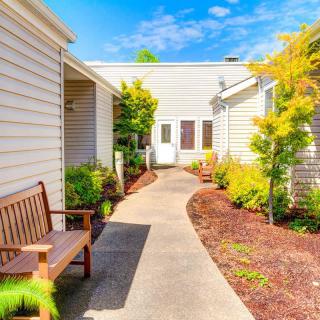 A serene outdoor pathway lined with plants and benches on a sunny day.