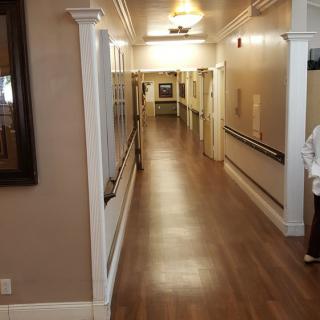 A long, well-lit hallway with wooden floors and handrails on the walls.