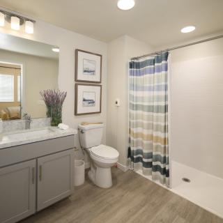 A modern bathroom interior with a shower curtain, sink, and toilet.