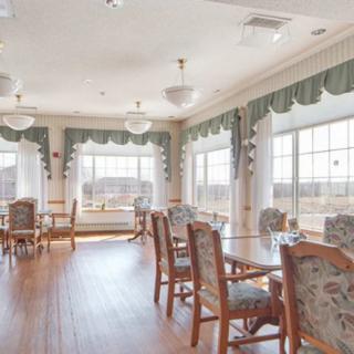 A bright and spacious dining room with wooden floors, large windows, and elegantly decorated tables and chairs.