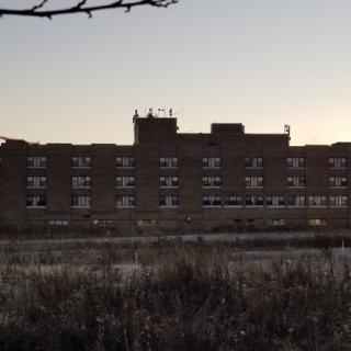 An abandoned building captured at dusk, surrounded by grasses.